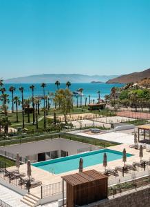 a view of a pool with palm trees and the ocean at Radisson Collection Hotel, Bodrum in Akyarlar
