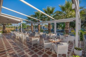 a restaurant with white chairs and tables and palm trees at Delfina Boutique Hotel in Georgioupolis