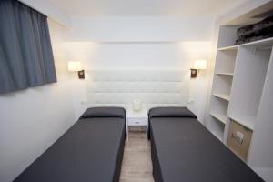 a room with two beds and a table and shelves at Pierre&Vacances Mallorca Portofino in Santa Ponsa +38 photos