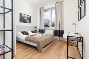 a white bedroom with a bed and a window at Apartments Warsaw Gagarina by Renters in Warsaw