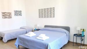 2 łóżka w pokoju z niebieską pościelą i ręcznikami w obiekcie Domus Garruba - Casa Vacanze Bari w mieście Bari