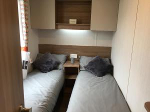 Habitación pequeña con 2 camas individuales y mesa. en 3 Bed Luxury Mobile Home Hoburne Park Christchurch, en Christchurch