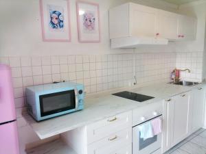 a white kitchen with a microwave and a sink at Lighane's Studio with Sailor Moon Room in Nuremberg
