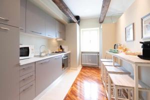 a kitchen with white cabinets and a wooden floor at RATAFIÀ Appartamento con vista sul lago in Orta San Giulio
