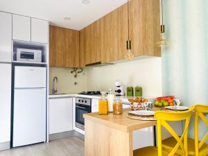 a kitchen with white appliances and a table with yellow chairs at Batata - Estúdios in Nazaré