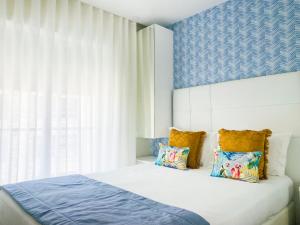 een slaapkamer met een wit bed met kussens en een raam bij Batata - Estúdios in Nazaré