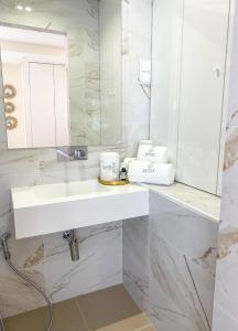 uma casa de banho branca com um lavatório e um espelho em Batata - Estúdios em Nazaré