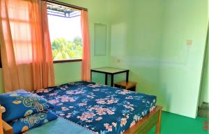 una camera da letto con un letto con un piumone blu e una finestra di Kendang Kempul Hostel a Dadapan