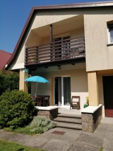 a house with a balcony with a table and an umbrella at Wakacje u Magdy in Rowy