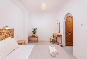 a white bedroom with a bed and a wooden door at Amalia in Matala