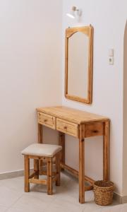 a wooden dressing table with a mirror and a stool at Amalia in Matala