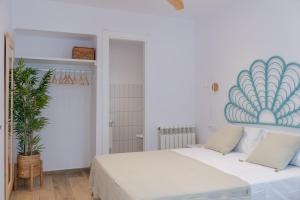 ein weißes Schlafzimmer mit einem Bett und einer Pflanze in der Unterkunft Apartamento mediterraneo, nuevo y acogedor de Eva in Sant Feliu de Guixols