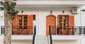 a house with orange doors and a palm tree at Amalia in Matala