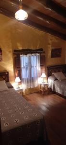 Benadalid的住宿－Casa rural El Patio，一间卧室设有两张床、两盏灯和一个窗户。
