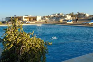 a swimming pool with blue water and buildings in the background at The Oasis in Abu Dabab