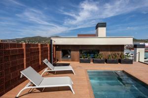 a patio with two chairs and a swimming pool on a roof at Art Apartments in Castelldefels