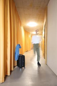 a man walking down a hallway with a suitcase at Guesthouse Kalkbreite in Zurich