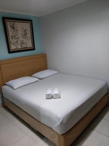 a bed with two white shoes on top of it at BLESSING RESIDENCE HOTEL in Jakarta