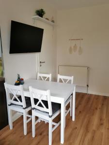 mesa de comedor blanca con sillas blancas y TV de pantalla plana en Casa Auszeit en Oranienburg