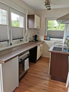 uma cozinha com um balcão de madeira e 2 janelas em Casa Auszeit em Oranienburg
