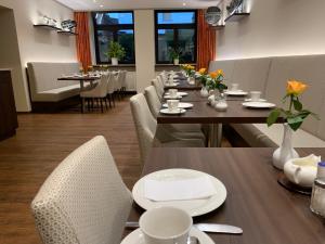 ein Esszimmer mit langen Tischen und weißen Stühlen in der Unterkunft Hotel Hübler in Frankfurt am Main