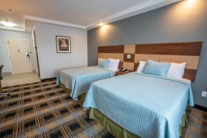 a hotel room with two beds with blue sheets at Hyannis Plaza Hotel in Hyannis