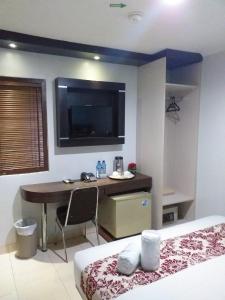 1 dormitorio con escritorio y TV en la pared en BLESSING RESIDENCE HOTEL, en Yakarta