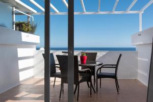 a table and chairs on a balcony with a view of the ocean at Maximilian House-Duplex vista al mar en complejo con piscina in Puerto del Carmen