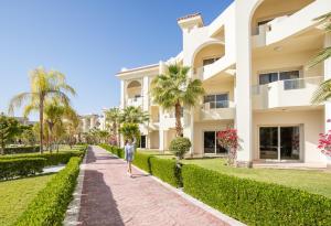 a person walking down a sidewalk in front of a building at SRNTY Sea Reef - Ex Serenity Alpha Beach in Hurghada