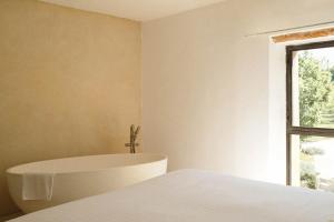 a bedroom with a white bed and a window at Le Galinier, a Beaumier hotel in Lourmarin
