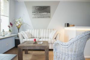 een woonkamer met een bank en een tafel en stoelen bij Haus-Holstein-Nr-5-App-3 in Westerland