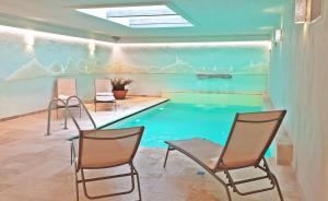 a swimming pool in a room with chairs in front of it at Kaska Ház in Tihany