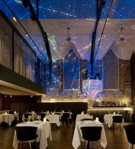 une salle à manger avec des tables blanches et des étoiles en toile de fond dans l'établissement Bodmin Jail Hotel, à Bodmin