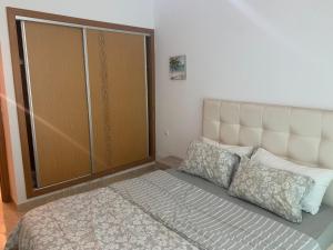 a bed with two pillows and a closet in a room at A 5 minutes à pied de la plage un bel appartement à saisir in Sidi Rahal