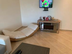 a living room with a white couch and a tv at A 5 minutes à pied de la plage un bel appartement à saisir in Sidi Rahal