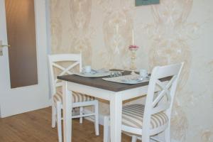 een eettafel met 2 stoelen, een witte tafel en een stoeltje bij Haus-Holstein-Nr-5-App-3 in Westerland