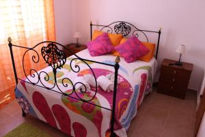 ラゴスにあるCasa Da Baíaのベッドルーム1室(カラフルなシーツと枕のベッド1台付)