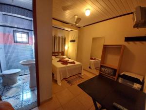a bedroom with a bed and a bathroom with a sink at Pousada Girar do Sol in Nova Friburgo