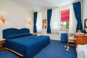 a bedroom with a blue bed and a desk and a window at Boutique & Beach Hotel Villa Wolff in Dubrovnik