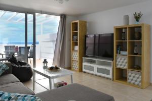 a living room with a couch and a tv at Maximilian House-Duplex vista al mar en complejo con piscina in Puerto del Carmen