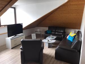 a living room with black leather furniture and a flat screen tv at Penthouse Mosel Huntress in Gornhausen