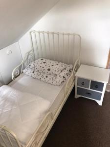 ein kleines weißes Bett mit einem Nachttisch daneben in der Unterkunft Penthouse Mosel Huntress in Gornhausen