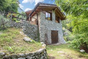 kamienny dom z drewnianymi drzwiami na wzgórzu w obiekcie Casa al mulino w mieście Tenno