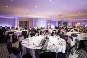 a banquet hall with white tables and chairs at Holiday Inn - Glasgow Airport by IHG in Paisley