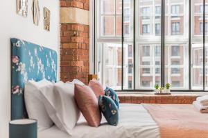 uma cama com almofadas num quarto com janelas em Chic one bed apartment- City Living in converted Cocoa Warehouse York PARKING em York