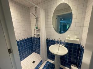 Baño de azulejos azules con lavabo y espejo en B&B aan de Hoofdkade, en Ter Apel