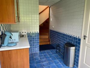 uma cozinha com azulejos azuis nas paredes e uma lata de lixo em B&B aan de Hoofdkade em Ter Apel