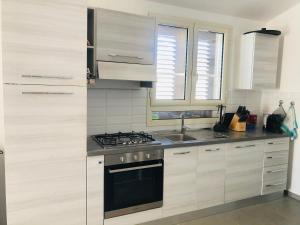 a kitchen with white cabinets and a stove top oven at Villa Melissa in Tertenìa
