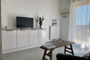 a living room with a tv on a white cabinet at Nouveau ! DoraMar : standing entre ville et mer in Montpellier
