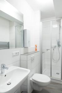 La salle de bains blanche est pourvue d'une douche et de toilettes. dans l'établissement Leben im Herzen von Fulda, à Fulde
